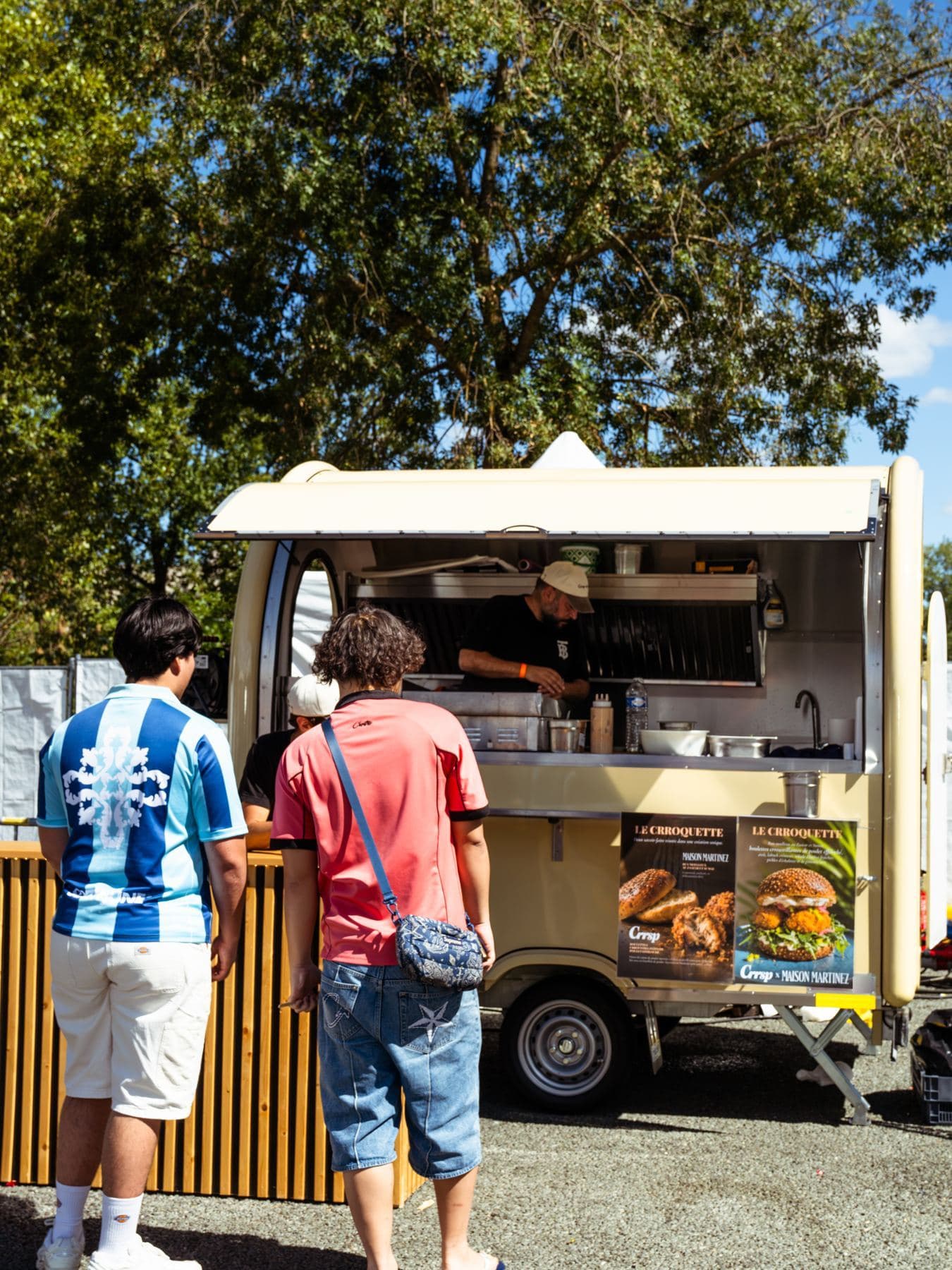 Beige verkoopwagen in volle drukte, klanten aan de toonbank